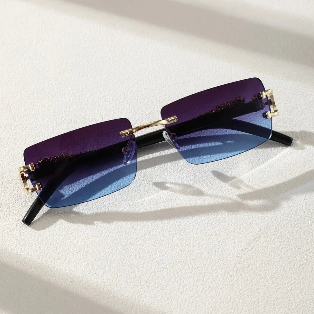 Rectangular sunglasses with gradient purple-to-blue rimless frames, UV400 protection, gold hinges, and black arms resting on a textured white surface with soft shadows.