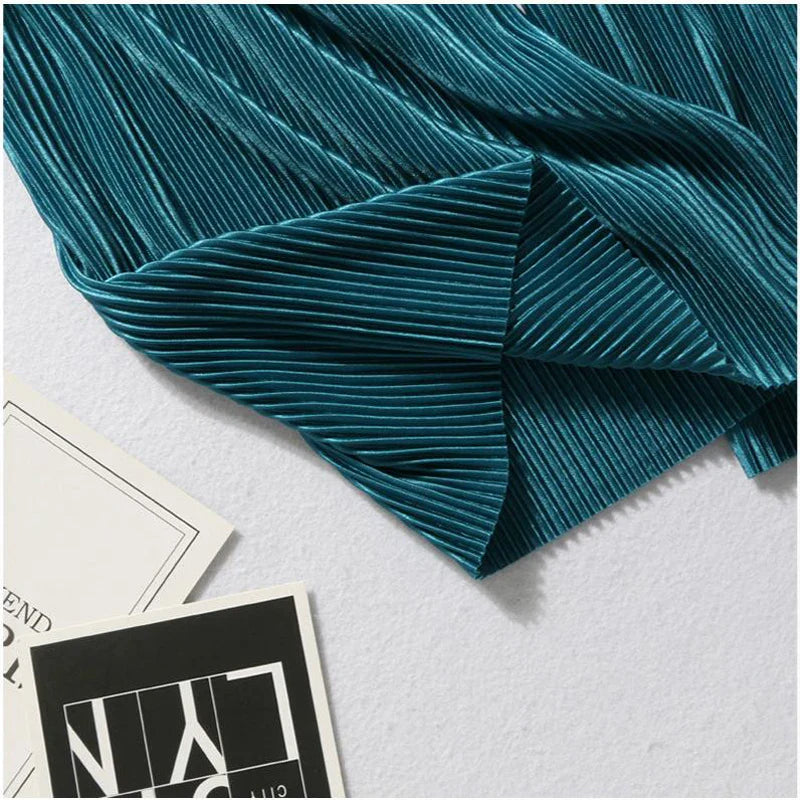 A close-up of teal Pleated Ice Silk fabric, reminiscent of Women Fashion Summer Pants, partially covering two black and white printed cards on a light-colored surface.
