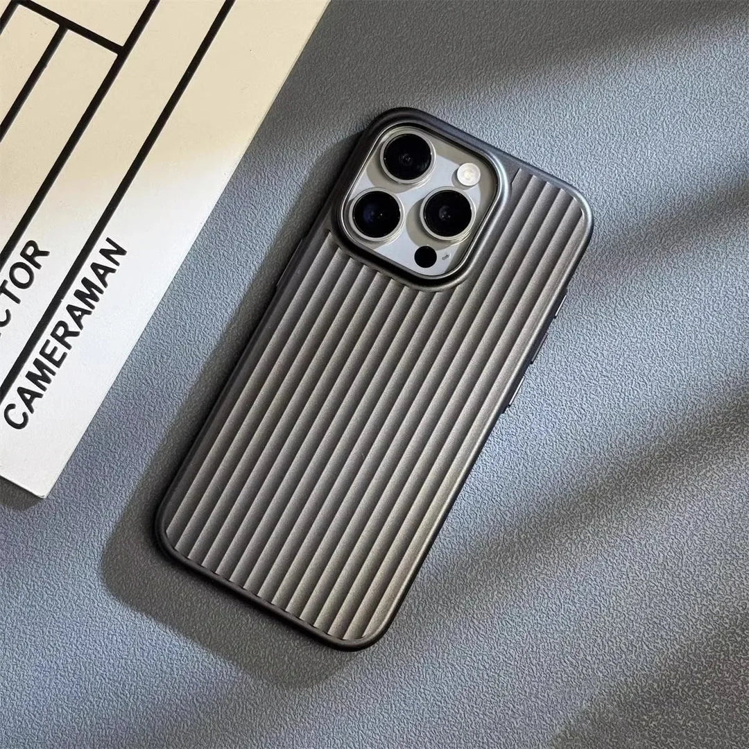 A smartphone with a slim lightweight design and ribbed gray case lies on a gray surface next to a white paper with the words CAMERAMAN and DIRECTOR partially visible. The phone’s three camera lenses are prominent.