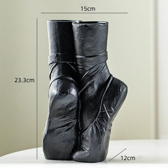 Black ceramic vase shaped like ballet shoes standing on tiptoe, 23.3 cm tall, 15 cm wide, and 12 cm deep. This ballet-inspired vase adds contemporary chic décor to any space, displayed on a white surface against a neutral background.