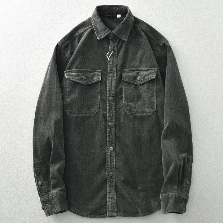 A dark gray, heavyweight cotton button-up shirt with corduroy detailing, long sleeves, a collar, and two chest pockets, laid flat on a light-colored surface.