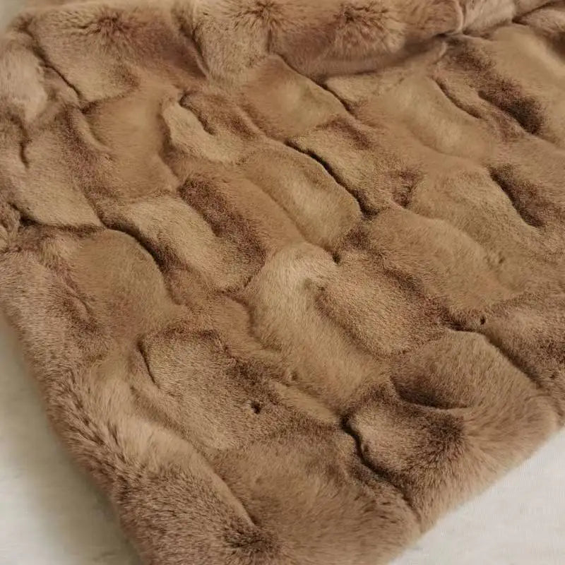 A close-up of plush faux fur fabric in light brown, with a textured, slightly wavy pattern, showing dense fibers and a shiny surface—perfect for an eco-friendly blanket or faux mink blanket.