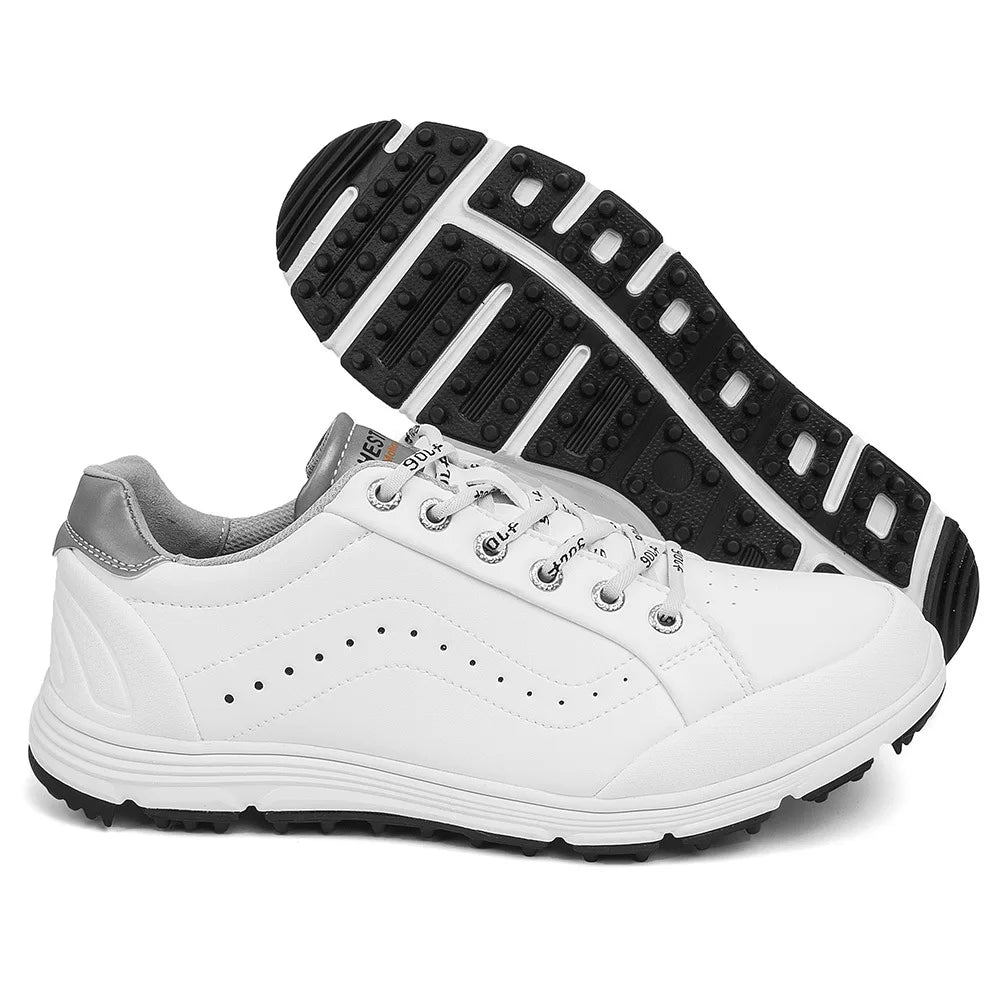 A pair of white golf footwear with gray accents, black soles, and decorative stitching. One shoe is upright while the other is tilted to showcase the textured sole and advanced cleat technology for enhanced performance on the course.