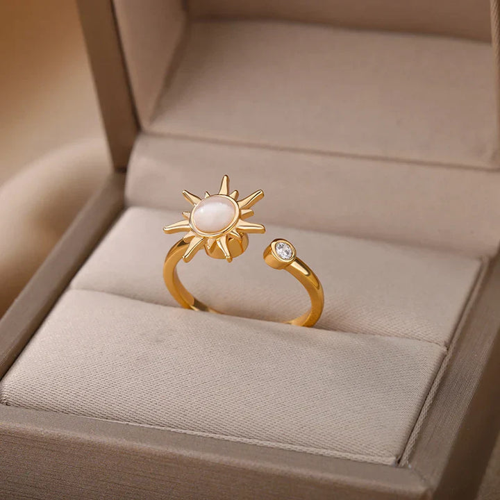 A stunning adjustable gold sun ring featuring a radiant sun-shaped design with a white center stone and a small round clear gemstone, beautifully displayed in a beige jewelry box.