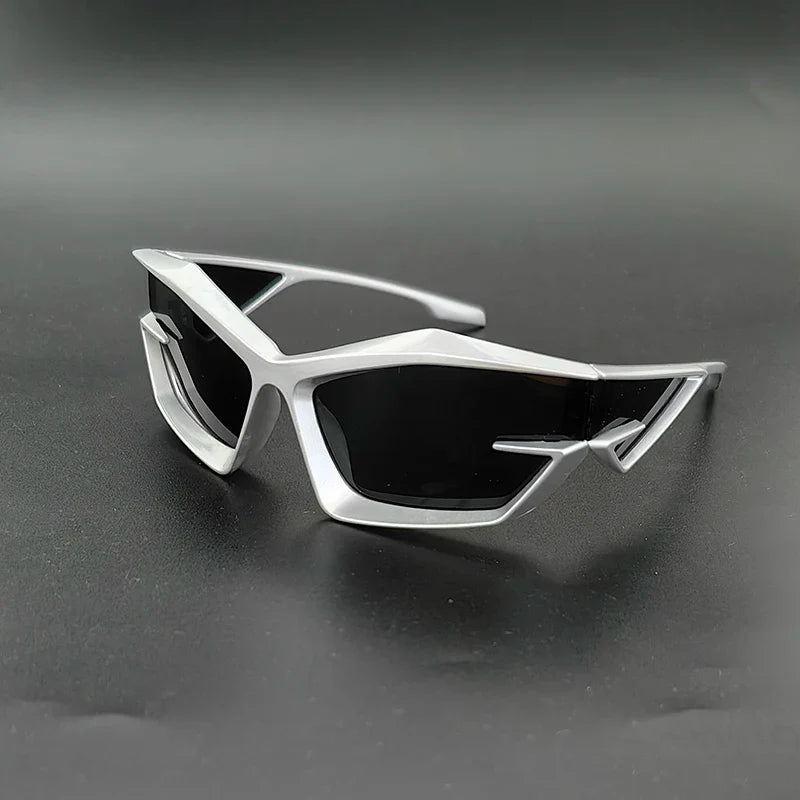 Futuristic silver sunglasses with angular, geometric frames and high-contrast lenses offering UV400 protection, displayed on a matte black surface.