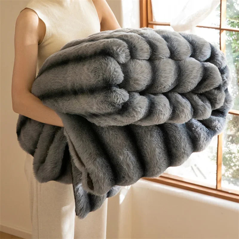 A person in light clothing holds a large, thick, luxurious throw with an elegant wave pattern in a sunlit room with a window and natural light in the background.