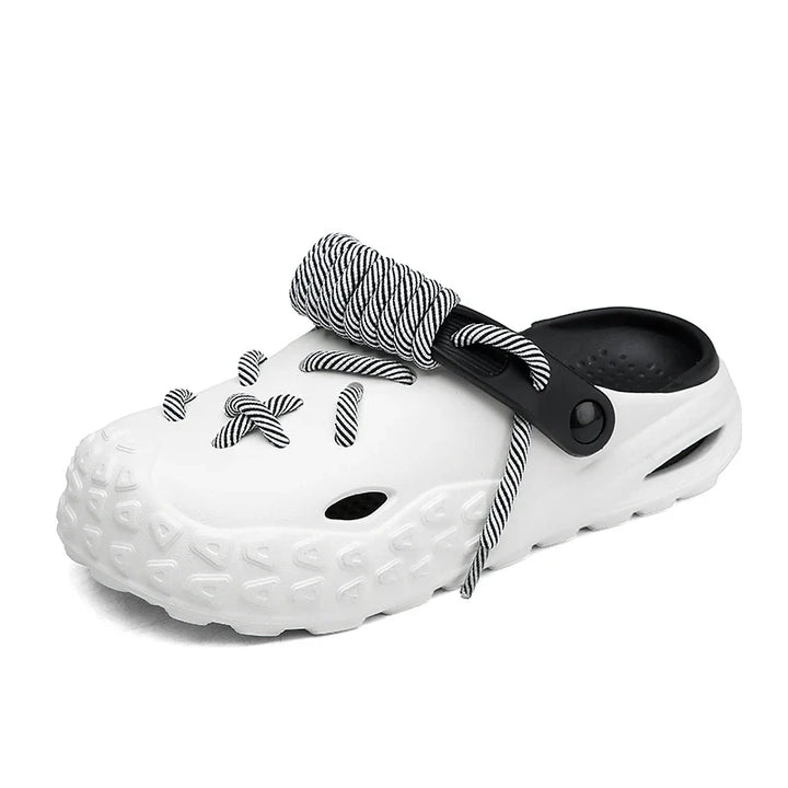 A white slip-on clog with a textured sole for enhanced grip, black interior, black back strap, and black-and-white striped lace detail threaded through holes on the top.