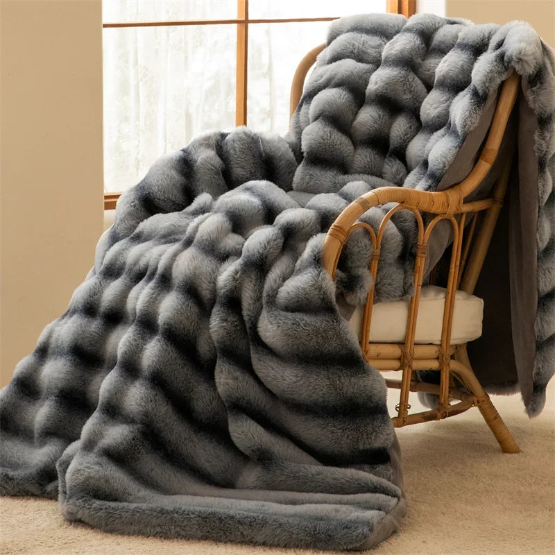 A luxurious throw with an elegant wave pattern, crafted from gray faux rabbit fur, drapes over a cushioned rattan chair next to a sunlit window, as soft natural light illuminates the cozy scene.