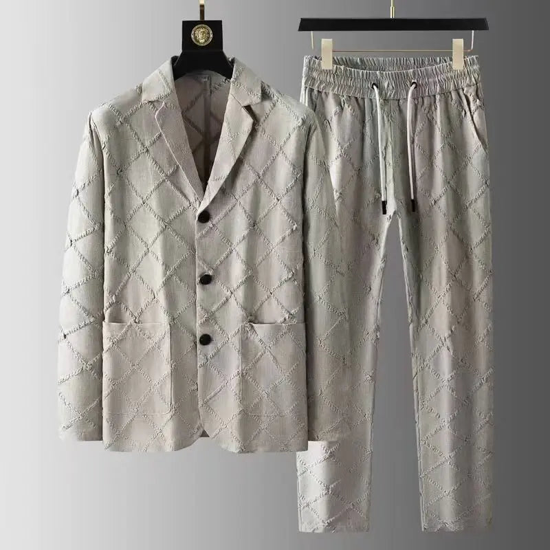 Light gray luxury two-piece set with a quilted diamond pattern, featuring a blazer with three black buttons and matching relaxed fit trousers, both displayed on hangers against a gradient gray background.
