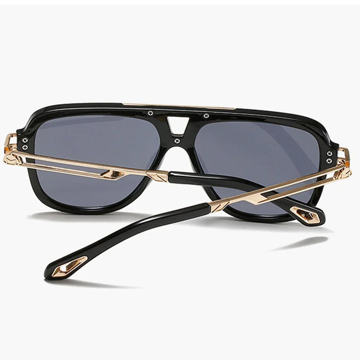A pair of black vintage sunglasses with gold accents, shown from the back with crossed temples and dark tinted lenses, against a plain white background.