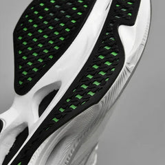 Close-up of the sole of a white sneaker with black and green tread pattern, featuring a textured, ultra-lightweight design for grip and style. The non-slip outsole adds stability for confident steps.