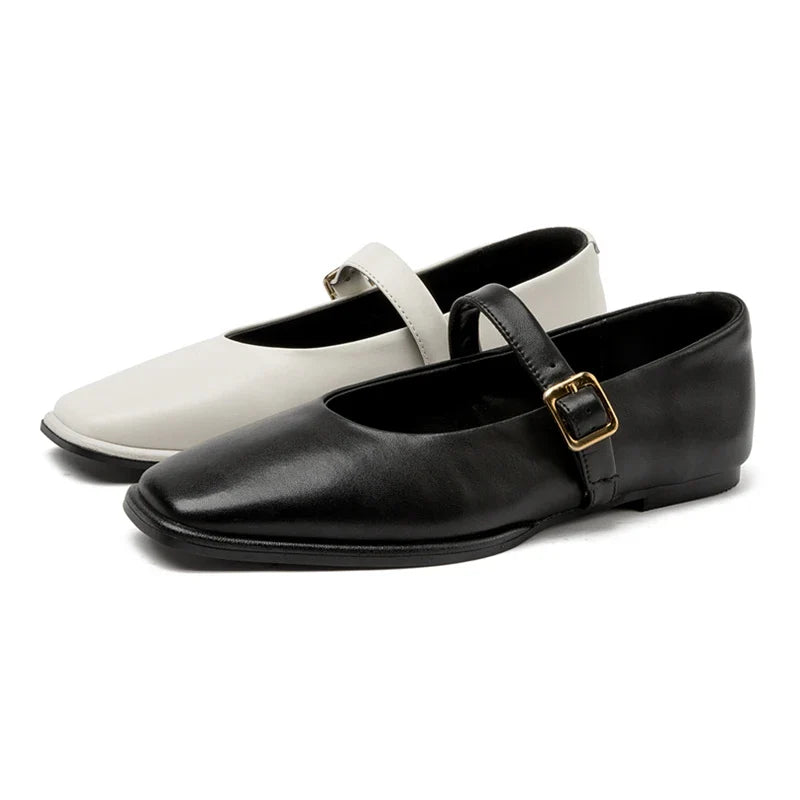 A pair of handmade leather flats, one black and one white, each with a gold buckle strap across the top. These Augusta Leather Ballet Flats showcase a simple, classic design and are placed side by side.