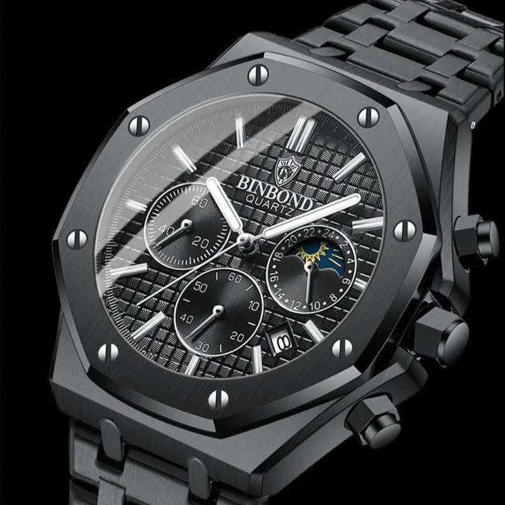 A close-up of a black BINBOND stainless steel watch with a textured dial, chronograph dials, date window, silver markers, and a metal link band on a black background.