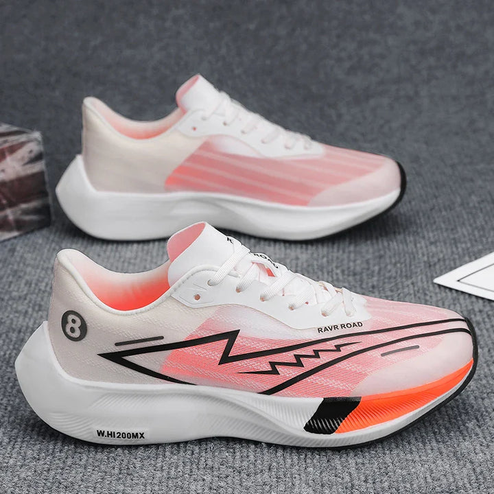 A pair of white and pink athletic sneakers with black zigzag designs, orange accents, and the number 8 on the heel, featuring a shock-absorbing sole, displayed on a gray textured surface.