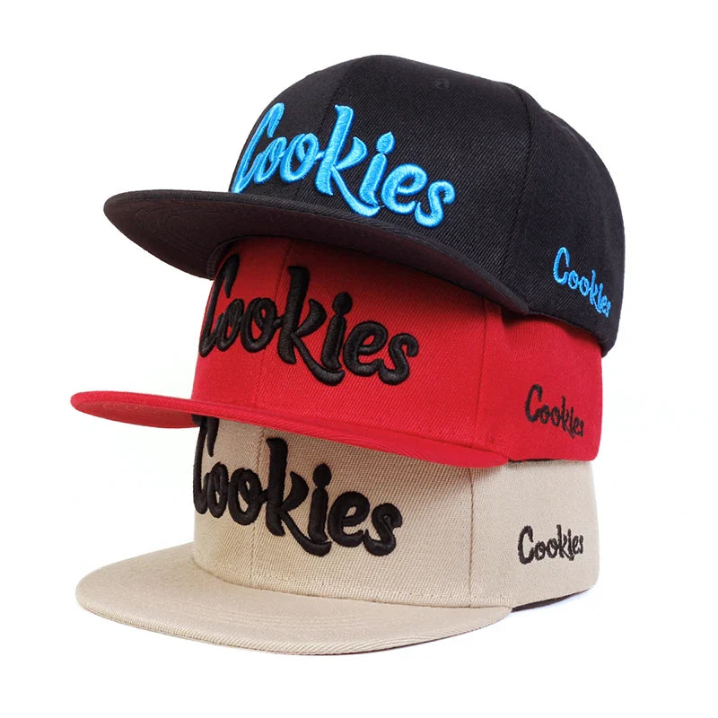 Three baseball caps stacked in black, red, and beige feature bold Cookies embroidery on the front and a smaller Cookies on the side. Each cap is crafted from breathable fabric for comfort and includes an adjustable strap for a custom fit.