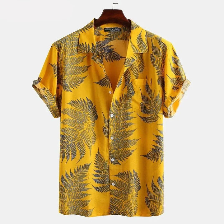 A short-sleeved, button-up cotton shirt in yellow with a classic black fern leaf pattern, perfect for a casual brunch, displayed on a wooden hanger against a plain white background.