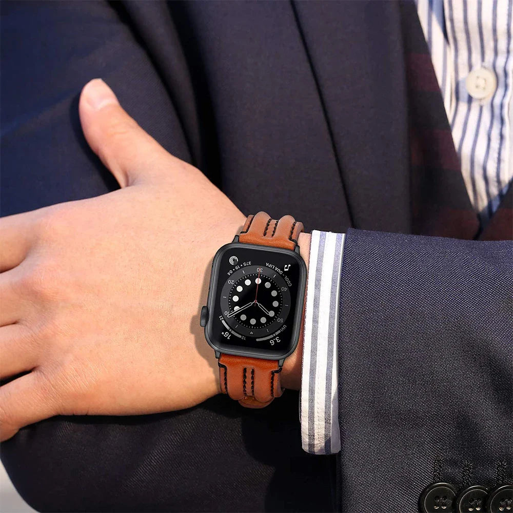 A person wearing a brown leather Apple Watch band with a black face, dressed in a navy blue suit and striped shirt, adjusts their sleeve.