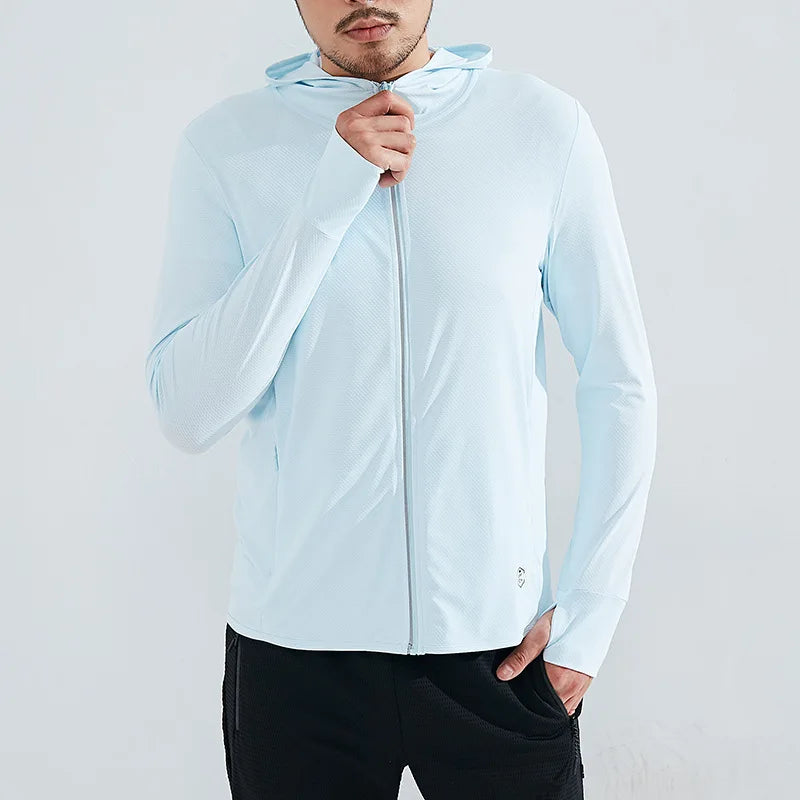 A person wearing a light blue UPF 50+ zip-up hoodie and black pants stands against a plain light background, with one hand holding the hoodie near their chin and the other in a pocket, enjoying sun protection and quick-drying fabric.