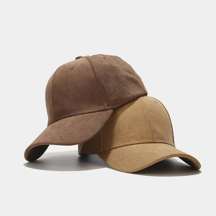 Two suede baseball caps, perfect as unisex streetwear caps, are stacked together against a plain white background. The brown cap rests on top of and slightly behind the tan cap.