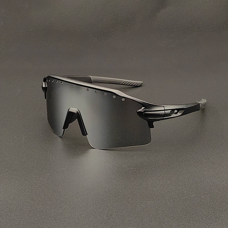 Futuristic, black oversized sunglasses with a single wraparound mirrored lens and sleek, angular frames, featuring UV400 protection, displayed on a gray surface.