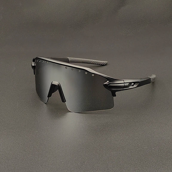 Futuristic, black oversized sunglasses with a single wraparound mirrored lens and sleek, angular frames, featuring UV400 protection, displayed on a gray surface.