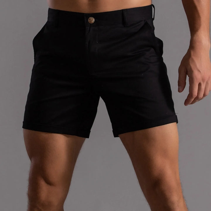 A person wearing black shorts with a semi elastic waistband and pockets, standing against a plain gray background. The image is cropped from mid-torso to mid-thigh.