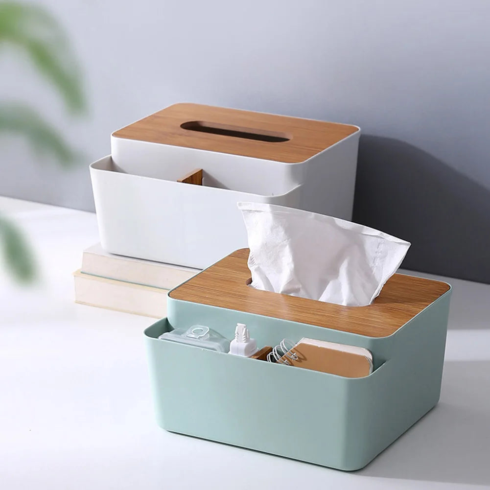 Two rectangular wooden cover storage boxes sit on a white surface; the front mint green desktop organizer holds tissues, lotion, and small items, while the white box with a wooden lid rests on two books in the back.