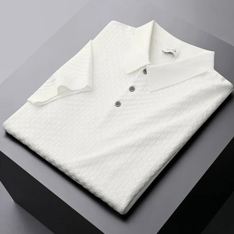 A neatly folded white waffle jacquard polo shirt with three buttons, placed on a dark gray surface.