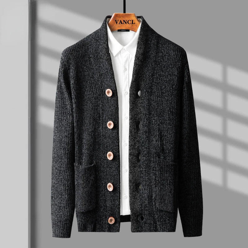A dark gray cardigan in a button up style with brown buttons is layered over a white collared shirt and displayed on a wooden hanger labeled VANCL against a gray background with shadow lines.