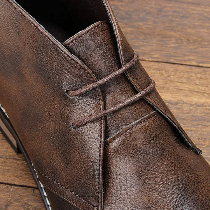 Close-up of a Western-inspired chukka on a wooden surface, highlighting the rich leather texture and detailed stitching.