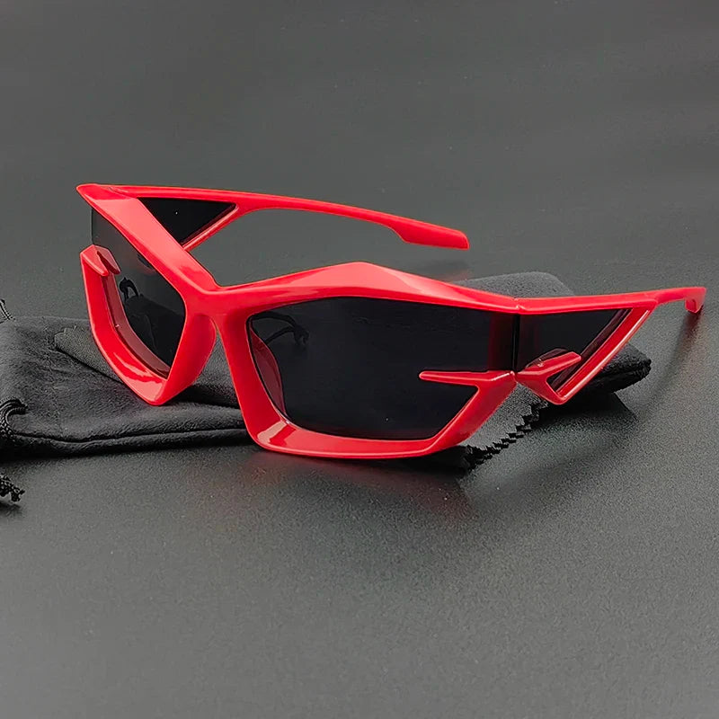 Red futuristic cycling glasses with geometric, angular frames and UV400 protection rest on a black cleaning cloth against a black background.