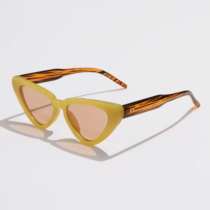Cat-eye sunglasses with pale yellow frames, brown tinted lenses, and orange-and-black patterned arms offer UV400 sun protection. This lightweight eyewear is displayed on a white surface.