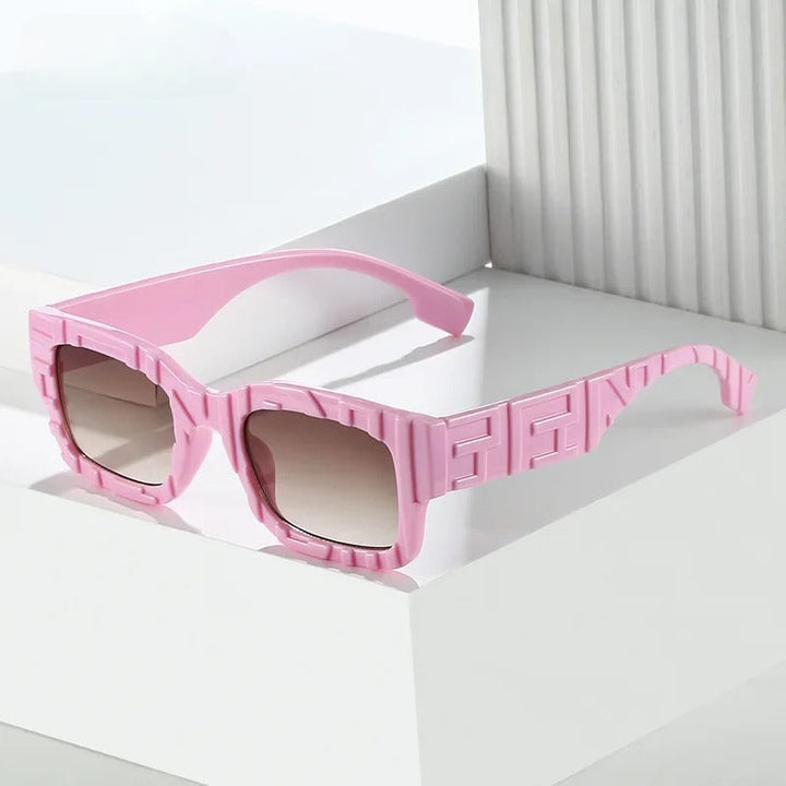 Pink square vintage sunglasses with thick, textured frames featuring a raised geometric pattern and UV400 protection, placed on a white, minimalist surface with vertical and horizontal lines in the background.