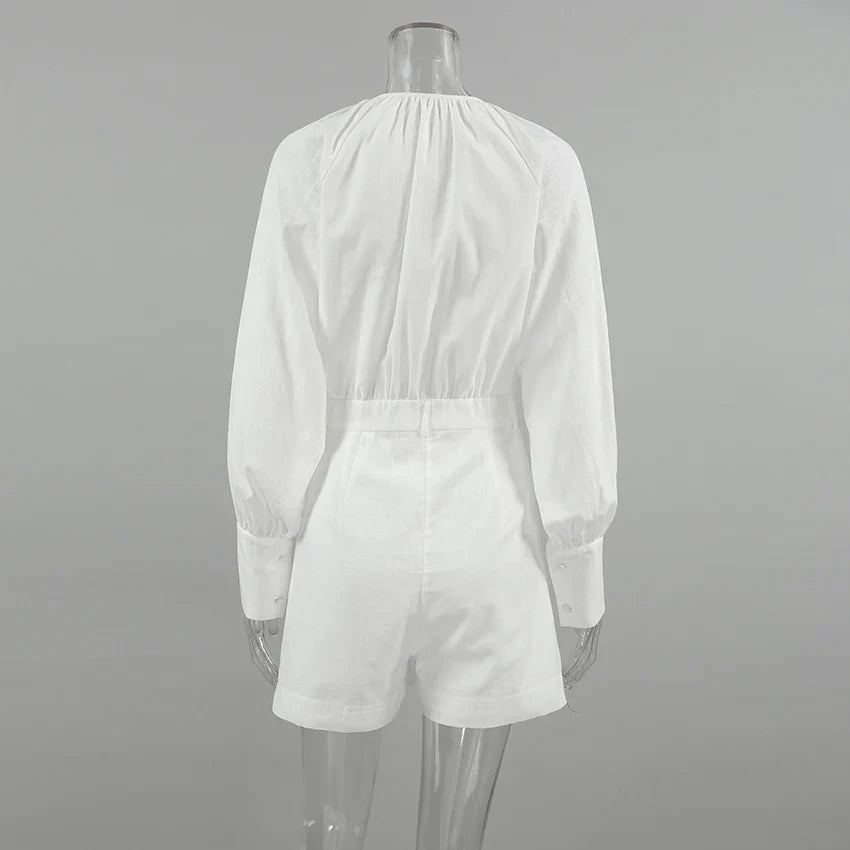 A clear mannequin displays a chic romper—white, long-sleeve, with an elastic waist and cuffed sleeves—shown from the back against a plain gray background. Perfect for a stylish summer outing.