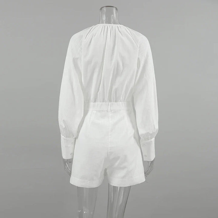 A clear mannequin displays a chic romper—white, long-sleeve, with an elastic waist and cuffed sleeves—shown from the back against a plain gray background. Perfect for a stylish summer outing.