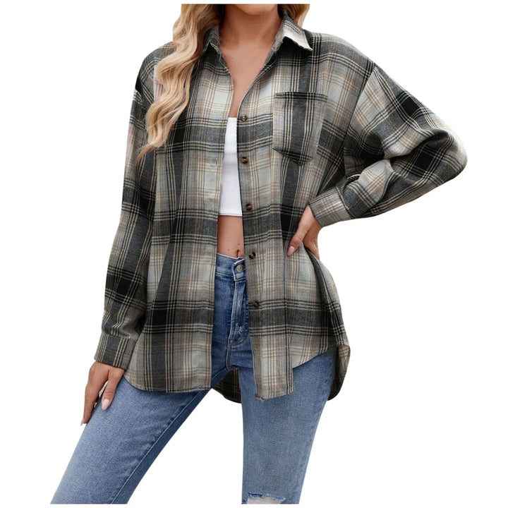 A woman wearing an oversized fit, long-sleeve plaid button-down over a white crop top and blue ripped jeans, posing with one hand on her hip. The shirt features a mix of gray, black, and beige tones—perfect for effortless layering.