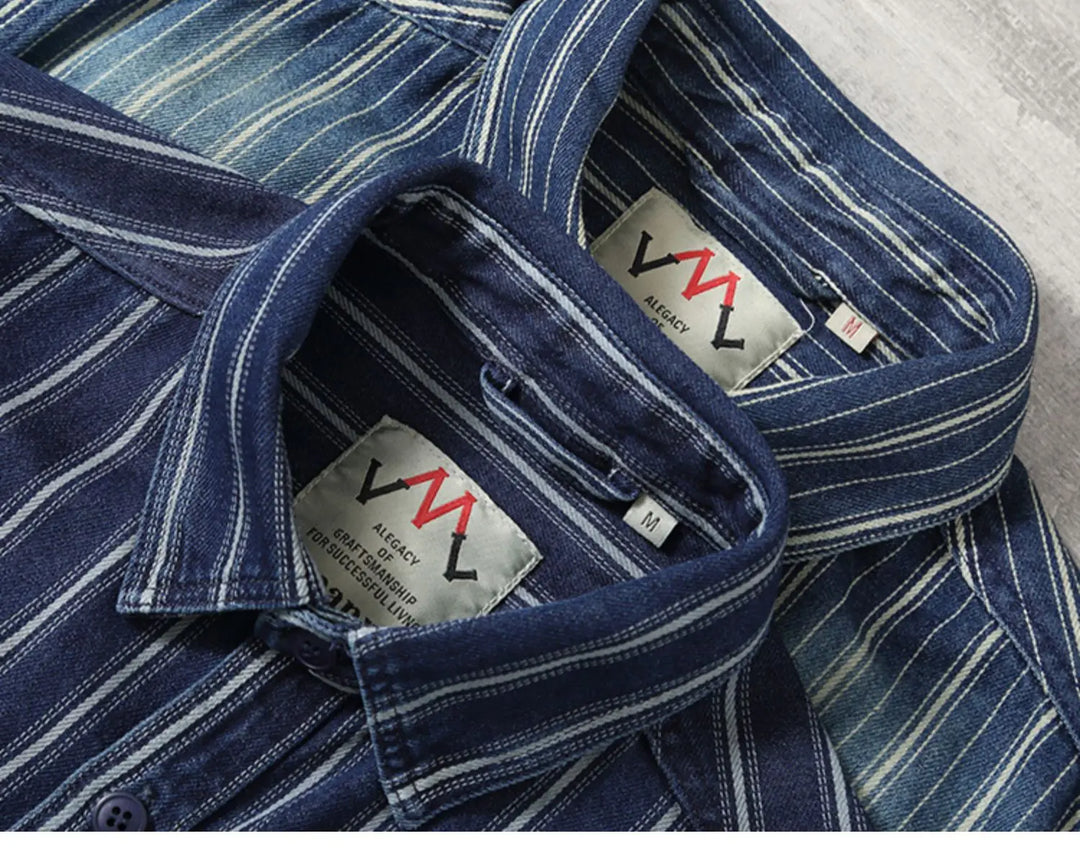 Two blue striped heavyweight cotton collared shirts with visible “AGENCY” labels and red “M” logos are laid side by side on a light surface, highlighting their relaxed fit, detailed collars, and fabric patterns.