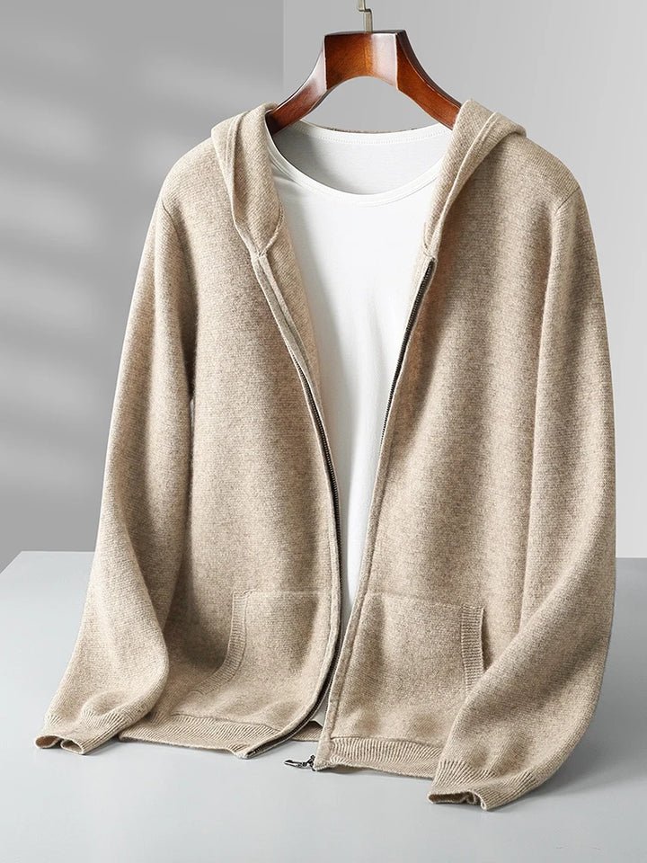 A beige zip-up hoodie with front pockets is displayed on a hanger over a white t-shirt, set against a light gray background with soft shadows—perfect for layering as an autumn winter sweater.