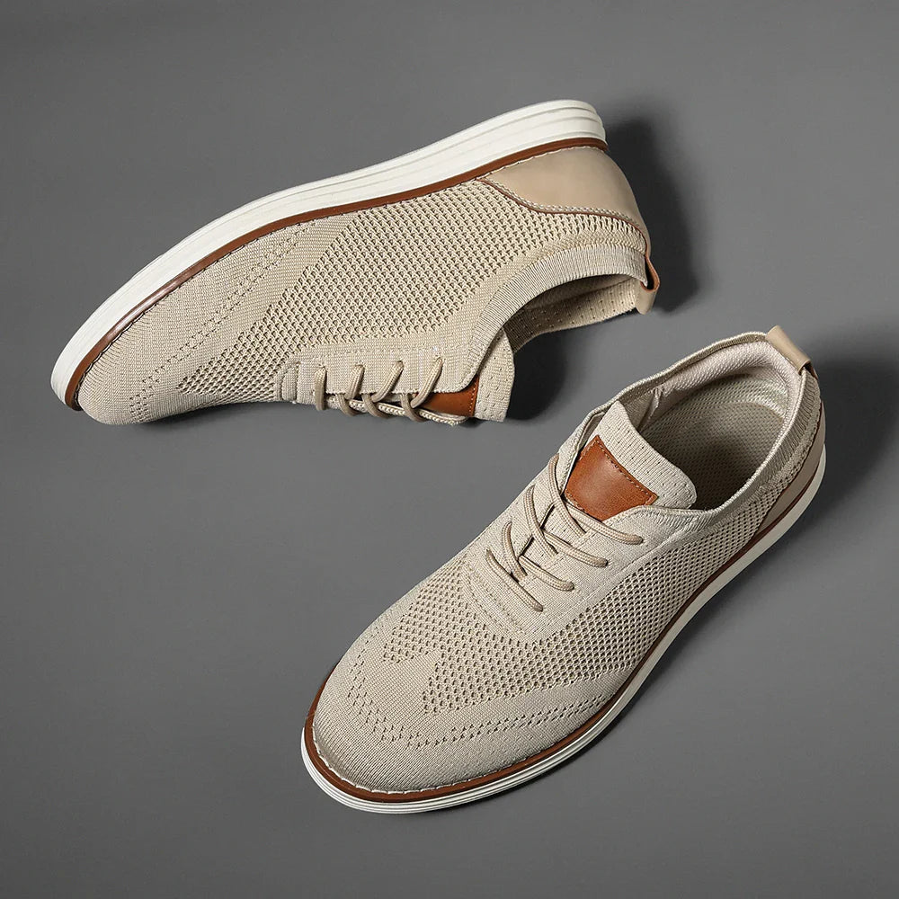 A pair of beige breathable knit sneakers with white soles and brown leather accents on the tongue and heel, perfect for casual style, displayed on a gray background.