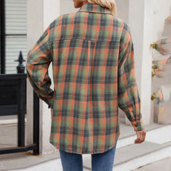 A person wearing an oversized fit, long-sleeve plaid button-down shirt in shades of orange, green, and black paired with blue jeans, standing outdoors with their back facing the camera.