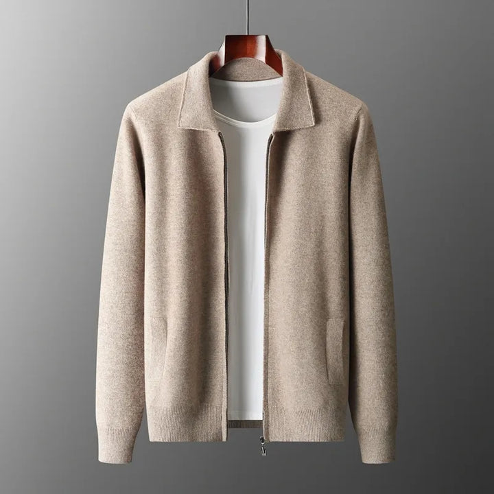 Beige zip-up cardigan with a collar, long sleeves, and two side pockets, crafted from moisture-wicking merino wool, displayed on a wooden hanger over a plain white t-shirt against a gray background.
