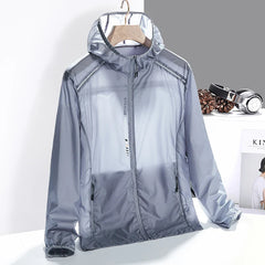 A lightweight, translucent gray hooded jacket made from quick-dry material with zippered pockets hangs on a wooden hanger against a gray and white background. Headphones and pinecones can be seen nearby.