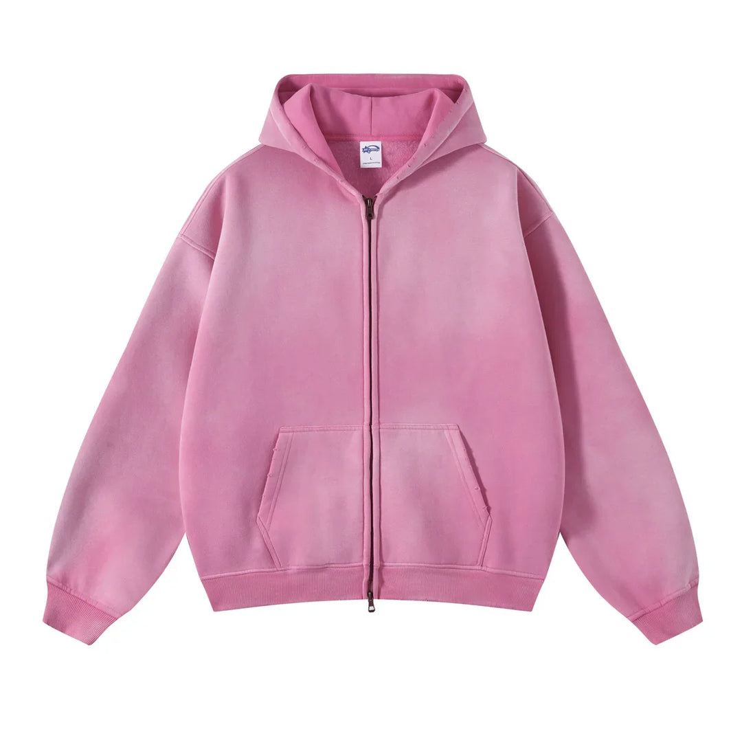 A pink zip-up hoodie with a relaxed fit, front pockets, and ribbed cuffs and hem features thickened fabric for extra warmth, displayed against a white background.