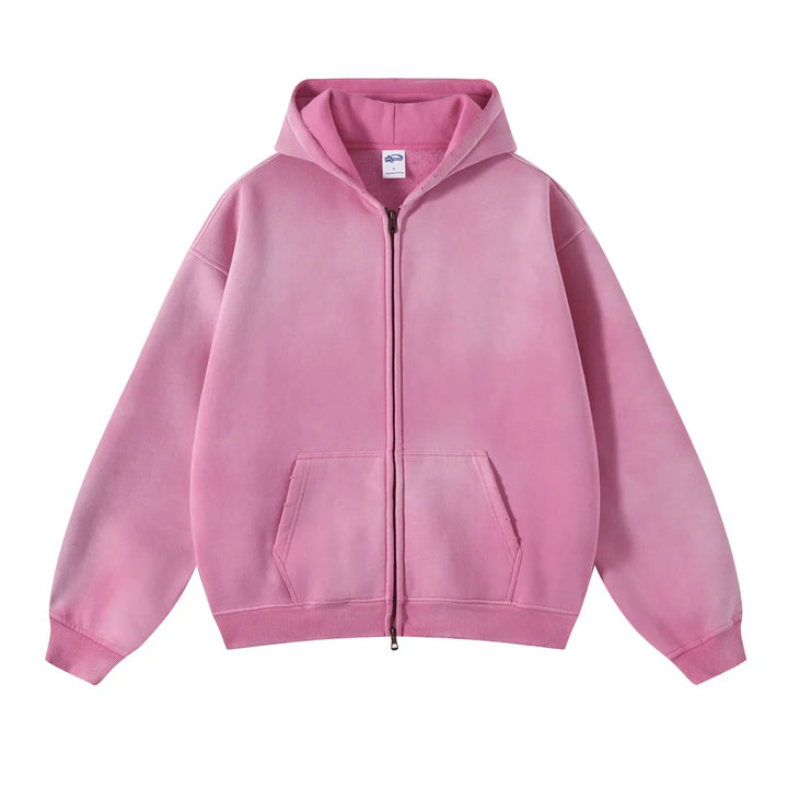 A pink zip-up hoodie with a relaxed fit, front pockets, and ribbed cuffs and hem features thickened fabric for extra warmth, displayed against a white background.