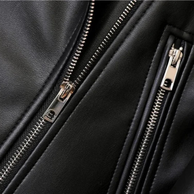 Close-up of a black leather jacket featuring two silver zippers and visible stitching, highlighting the texture of the leather, details of the metal zipper teeth and pulls, and an adjustable waist belt.