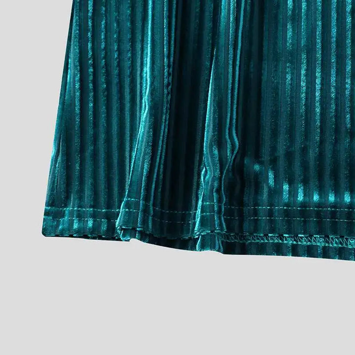 Close-up of the hem of a teal, vertically striped velvet fabric skirt, featuring anti-wrinkle technology for a smooth finish and showcasing the texture and subtle sheen of the material against a plain light background.