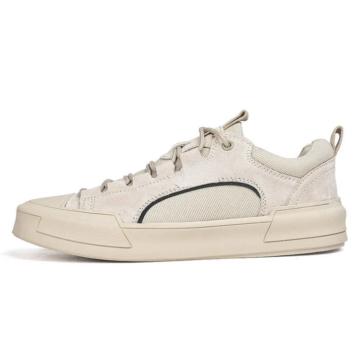A beige low-top suede canvas shoe with a thick, durable rubber outsole, lace-up front, subtle black detailing on the side, and a pull tab at the heel, shown in side profile against a white background.