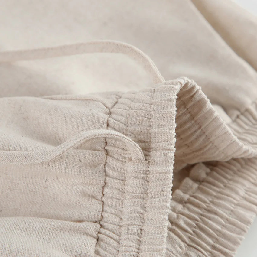 Close-up of beige Belgian Linen Blend shorts featuring an elastic waistband and a drawstring, highlighting the texture and stitching details.