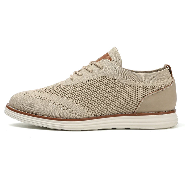 A beige breathable knit sneaker with a white sole, light brown accents, and laces. This lightweight sneaker features a mesh design and sleek, casual style, perfect as business casual shoes. Viewed from the side on a plain white background.