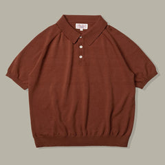 A short-sleeved brown organic cotton polo with a ribbed hem and sleeves, three white buttons, and a classic collar, laid flat on a neutral gray background.